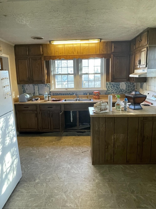 kitchen featuring decorative backsplash, dark brown cabinets, a textured ceiling, sink, and white refrigerator