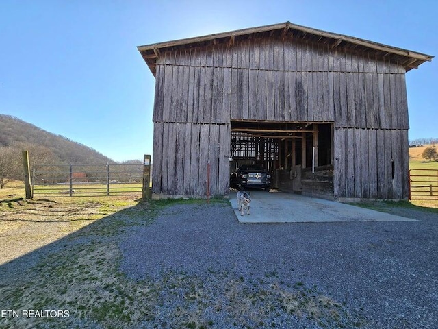 view of barn featuring driveway and fence