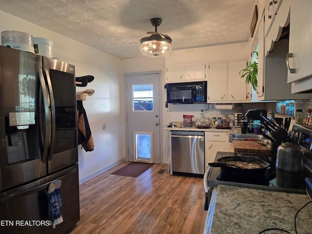 kitchen featuring white cabinetry, light countertops, a textured ceiling, appliances with stainless steel finishes, and wood finished floors