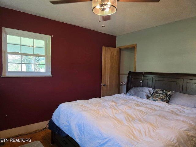 bedroom with ceiling fan, wood finished floors, and baseboards