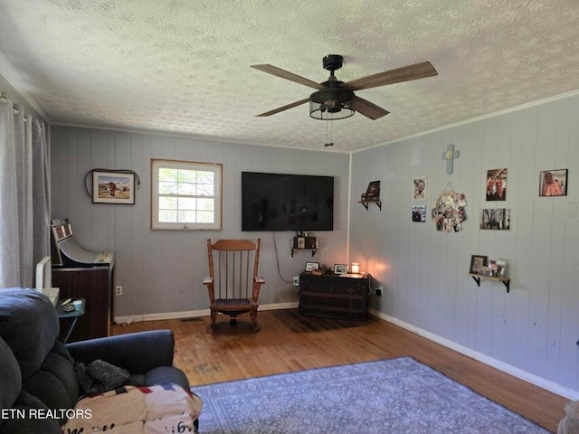 living room featuring baseboards, wood finished floors, a ceiling fan, and a textured ceiling