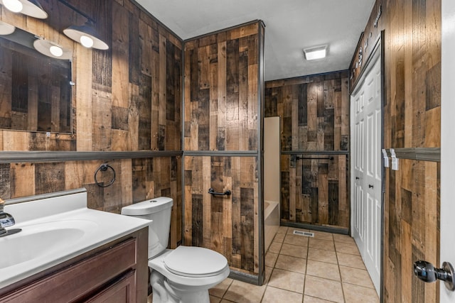 bathroom featuring vanity, wooden walls, tile patterned flooring, toilet, and a textured ceiling