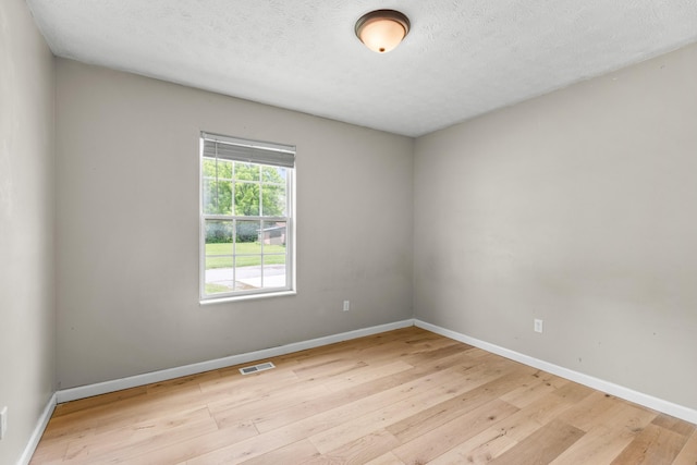 spare room featuring a textured ceiling and light hardwood / wood-style floors