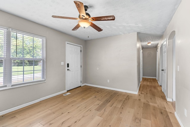 spare room with ceiling fan, light hardwood / wood-style floors, and a textured ceiling