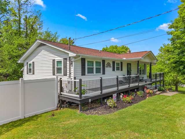 rear view of property with a yard, a deck, fence, and roof with shingles
