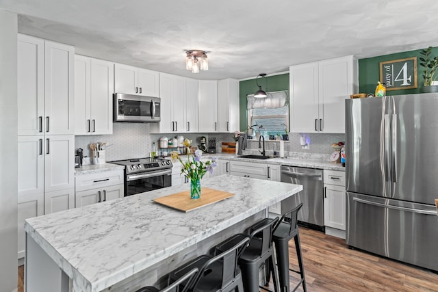 kitchen with white cabinets, a kitchen breakfast bar, appliances with stainless steel finishes, and a sink