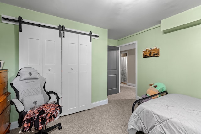 bedroom featuring carpet floors, baseboards, and a barn door