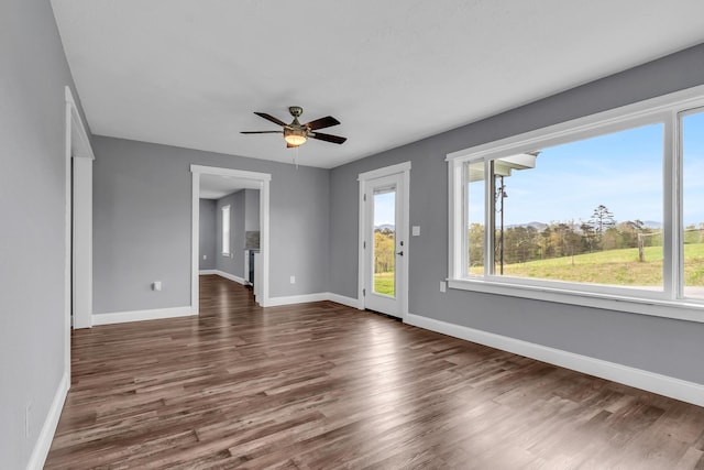 empty room with ceiling fan, dark hardwood / wood-style flooring, and a healthy amount of sunlight