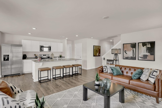 living area featuring baseboards, light wood-type flooring, and recessed lighting