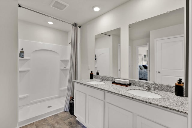 full bath with ensuite bath, a shower stall, visible vents, and a sink