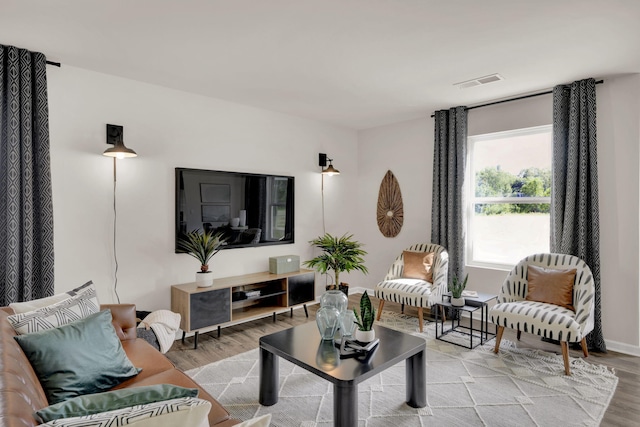 living area with visible vents and wood finished floors