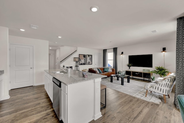 kitchen featuring open floor plan, a sink, stainless steel dishwasher, and wood finished floors