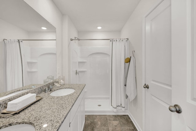 full bathroom featuring double vanity, a shower stall, and a sink