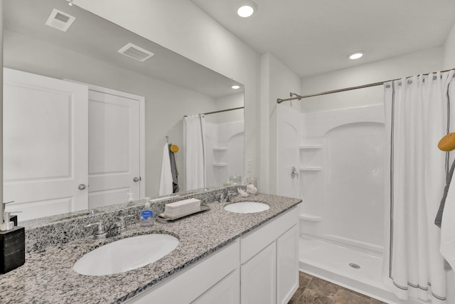 bathroom featuring double vanity, a sink, visible vents, and a shower stall