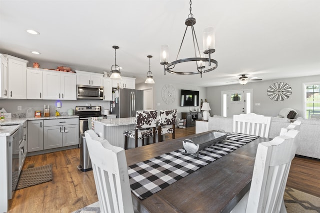 dining space featuring recessed lighting, dark wood-style floors, and ceiling fan with notable chandelier