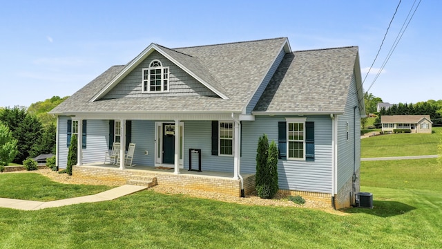 view of front of house featuring a shingled roof, covered porch, and a front yard