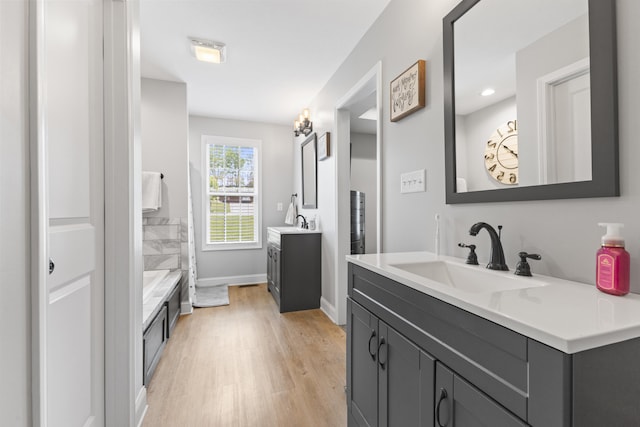 bathroom with two vanities, wood finished floors, a sink, and baseboards