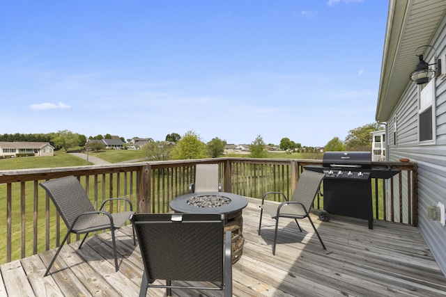 wooden deck featuring an outdoor fire pit, a yard, and a grill