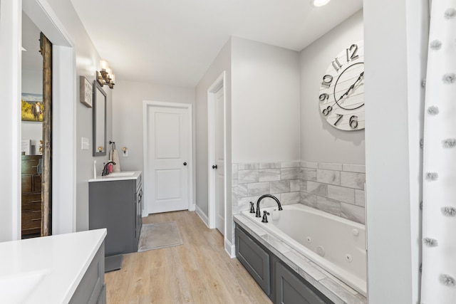 full bathroom with baseboards, a whirlpool tub, wood finished floors, and vanity