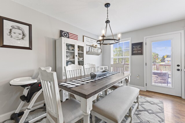 dining area featuring light wood-type flooring, baseboards, and an inviting chandelier