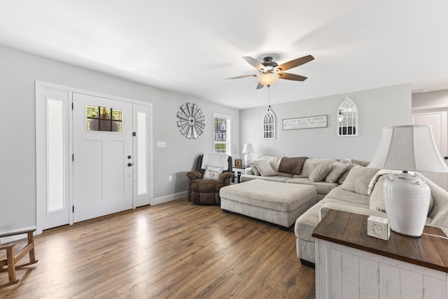 living room featuring baseboards, a wealth of natural light, ceiling fan, and dark wood finished floors