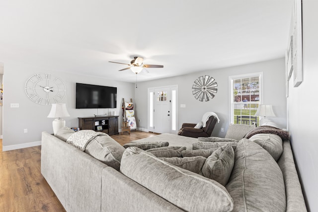 living area with ceiling fan, baseboards, wood finished floors, and plenty of natural light