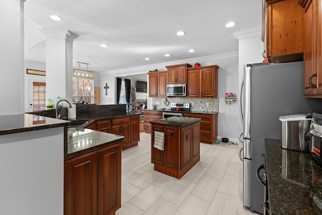 kitchen with a kitchen island, appliances with stainless steel finishes, dark stone counters, ornamental molding, and kitchen peninsula