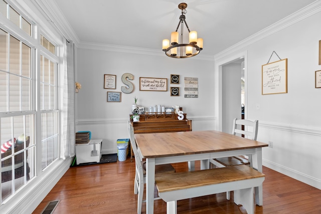 dining space with hardwood / wood-style flooring, ornamental molding, a healthy amount of sunlight, and a chandelier