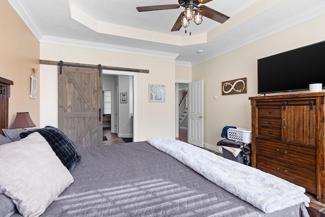 bedroom with ceiling fan, ornamental molding, a barn door, and a raised ceiling