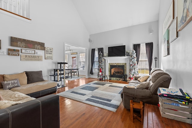 living room with hardwood / wood-style flooring, a premium fireplace, and high vaulted ceiling