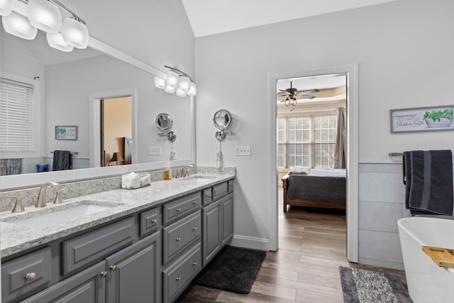 bathroom featuring vanity, vaulted ceiling, ceiling fan, and a tub to relax in