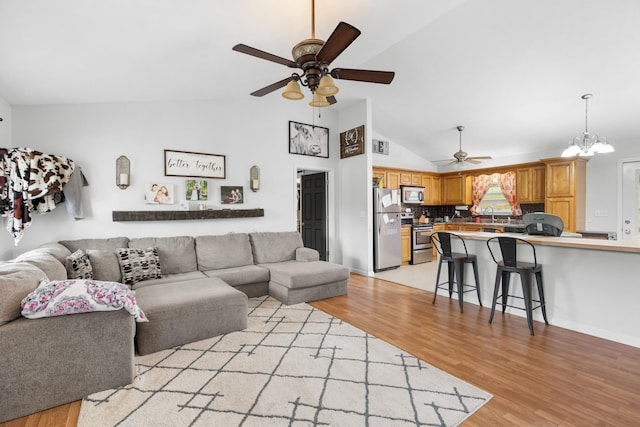 living room with light wood finished floors, ceiling fan with notable chandelier, and high vaulted ceiling