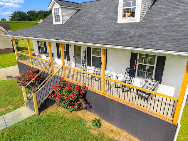 cape cod-style house featuring a porch, a front yard, and roof with shingles