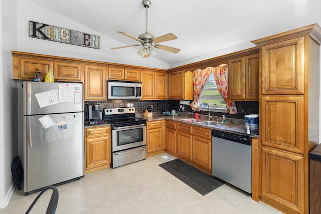 kitchen featuring decorative backsplash, dark countertops, a sink, lofted ceiling, and stainless steel appliances