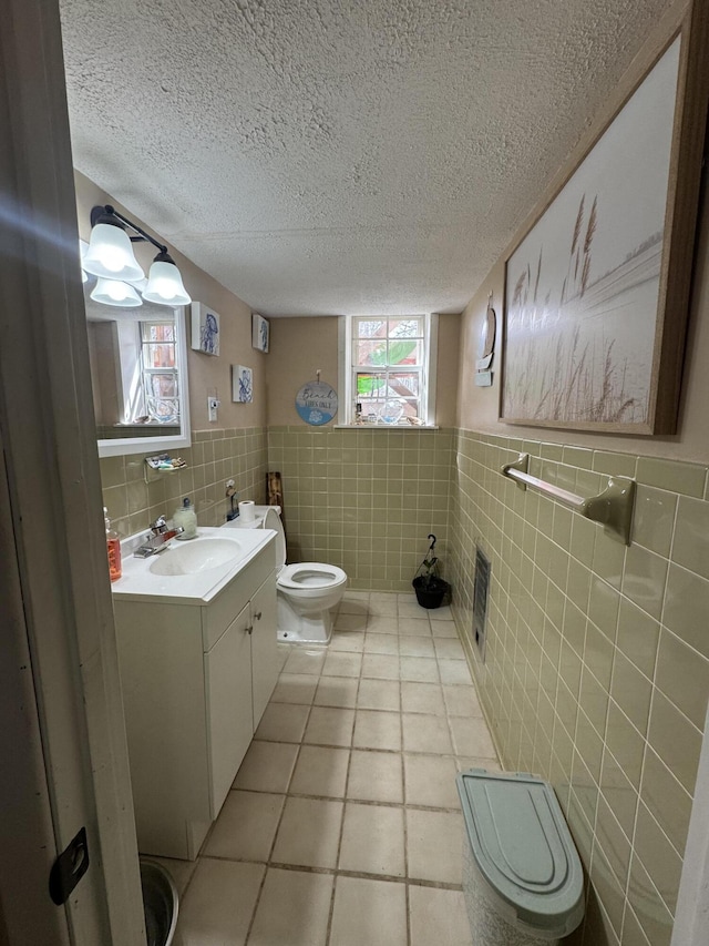 half bath featuring toilet, a textured ceiling, tile walls, tile patterned flooring, and vanity