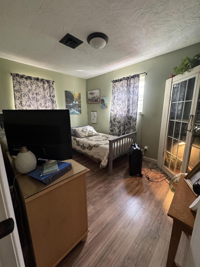 bedroom featuring wood finished floors, baseboards, and a textured ceiling