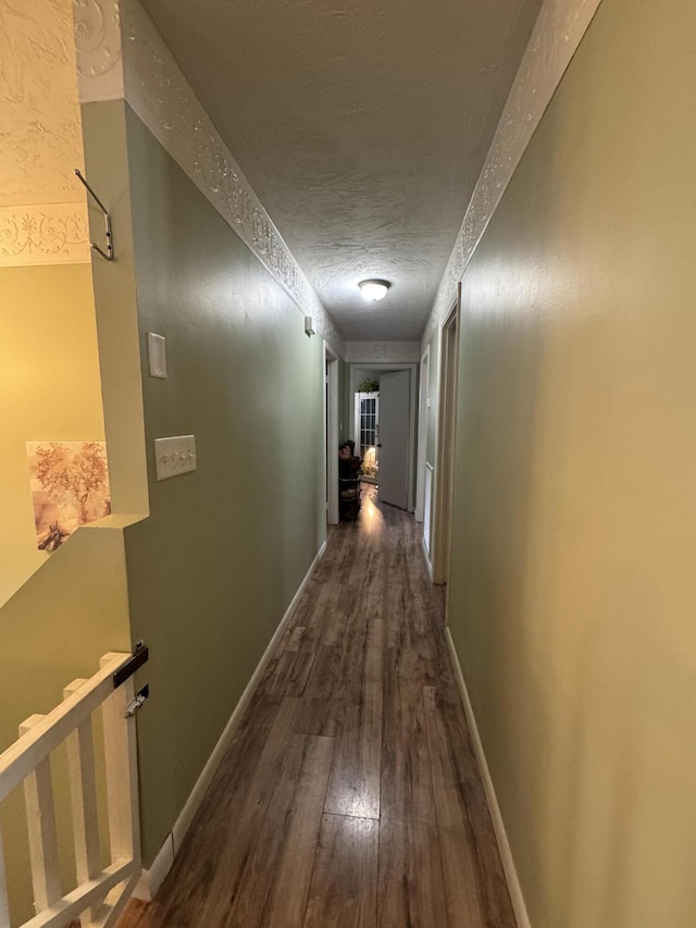 hall with baseboards, an upstairs landing, a textured ceiling, and wood finished floors