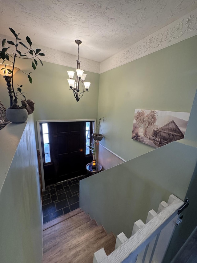 entryway with stairway, wood finished floors, a chandelier, and a textured ceiling