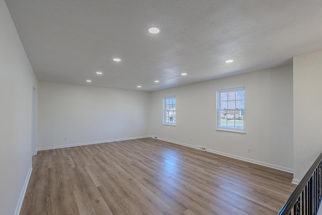 spare room featuring a textured ceiling and light hardwood / wood-style floors