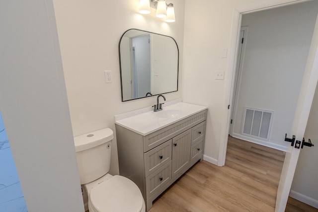 bathroom with toilet, vanity, and hardwood / wood-style floors