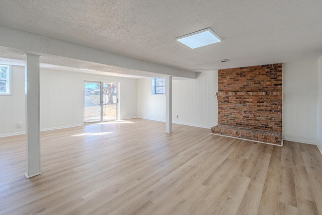 basement with a textured ceiling, wood walls, and light hardwood / wood-style floors