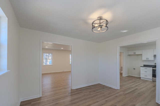 spare room featuring light hardwood / wood-style floors and a chandelier