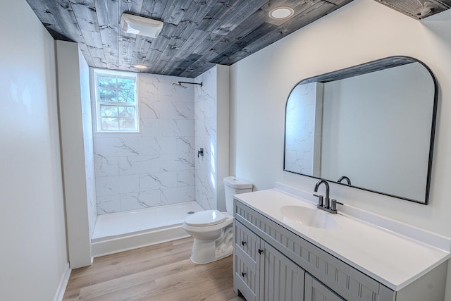 bathroom featuring toilet, a tile shower, hardwood / wood-style floors, wooden ceiling, and vanity