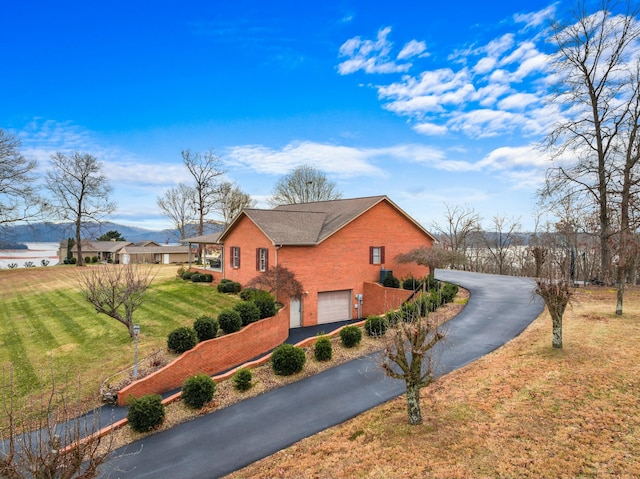 view of side of property with a yard, a water view, and a garage