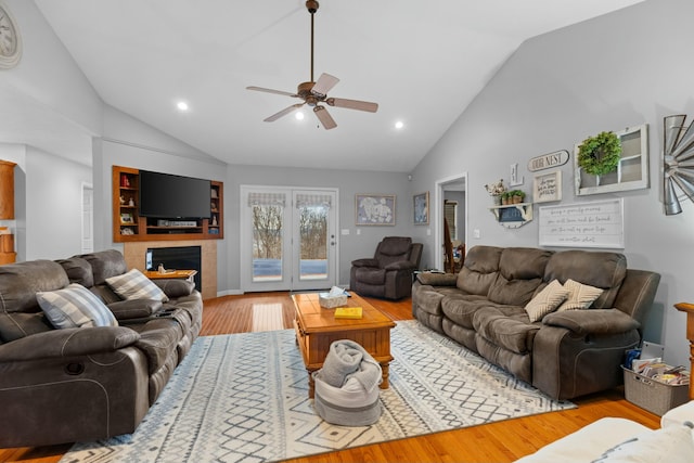 living room with ceiling fan, light hardwood / wood-style floors, a fireplace, and vaulted ceiling