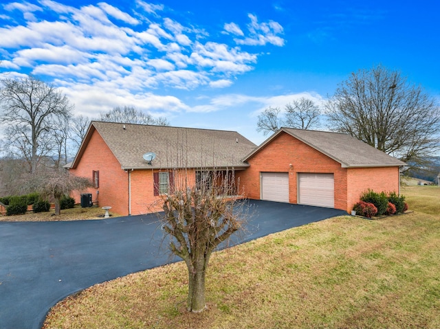 view of front of house with cooling unit, a garage, and a front yard