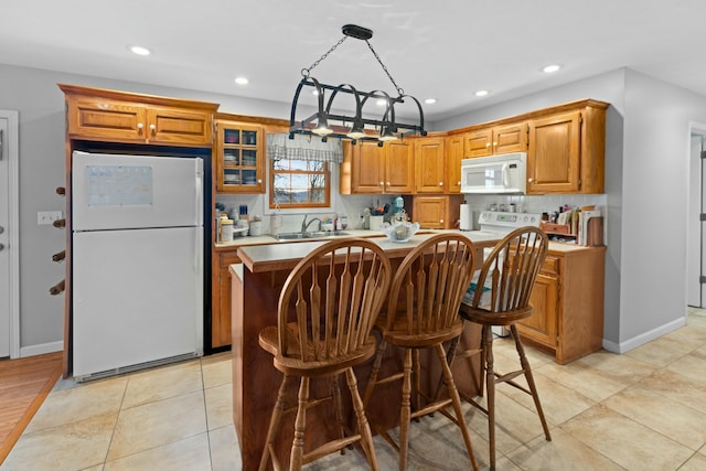 kitchen featuring decorative backsplash, white appliances, sink, a notable chandelier, and a kitchen island