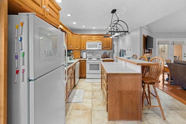 kitchen with pendant lighting, white appliances, a kitchen breakfast bar, a kitchen island, and light tile patterned flooring