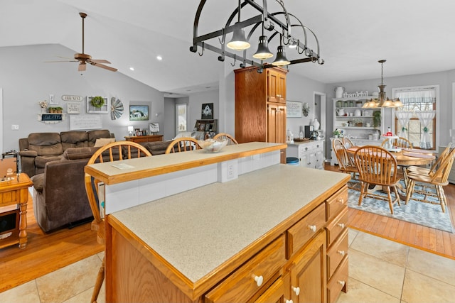 kitchen with a center island, lofted ceiling, decorative light fixtures, light tile patterned floors, and ceiling fan with notable chandelier