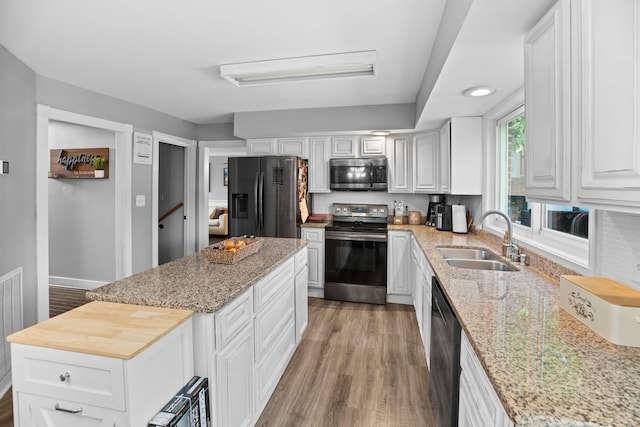 kitchen featuring a kitchen island, light wood-type flooring, appliances with stainless steel finishes, white cabinetry, and a sink